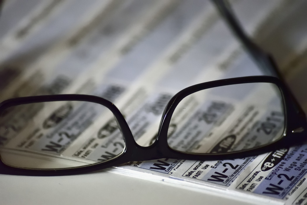 reading-glasses-placed-on-top-of-business-personal-tax-forms-side-angle-at-low-angle-close-up-view_t20_knWjYR